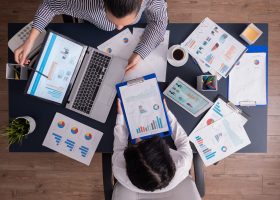 vista-superior-gerente-empleado-que-trabajan-equipo-oficina-negocios-mirando-graficos-pantalla-computadora-portatil-scaled